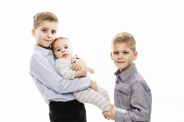 Two brothers are holding a newborn. Love and tenderness in the family. White background. - Foto, Bild
