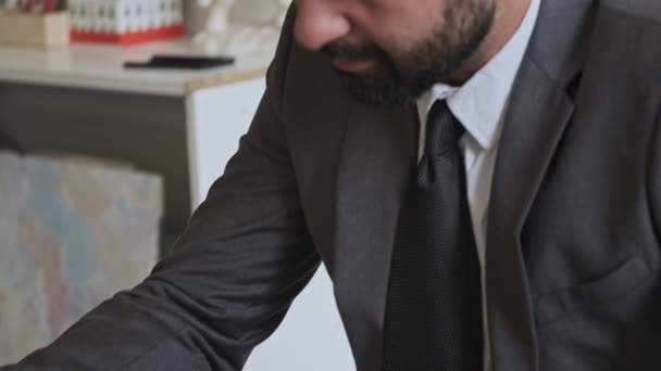 Close up view of Concentrated handsome bearded businessman writing something at office - Materiaali, video
