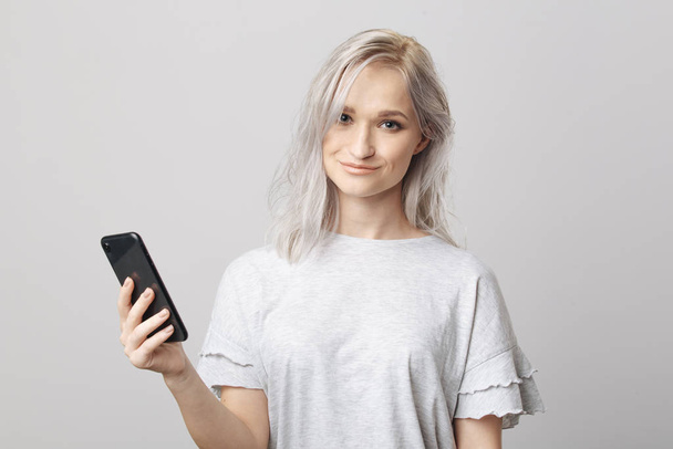 Happy blond woman in studio holding phone. - Photo, Image