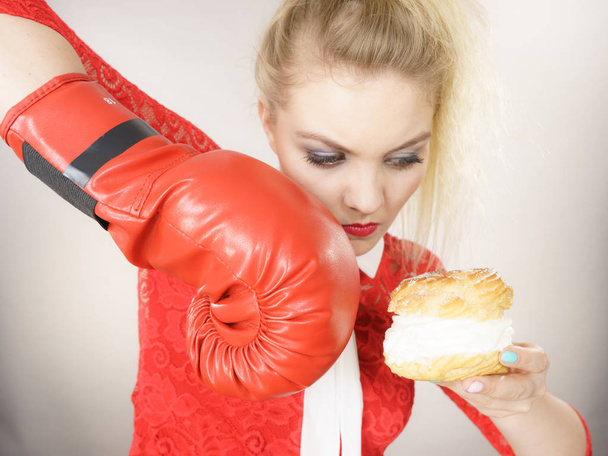 Woman fighting off bad food, boxing cream puff cake - Foto, imagen