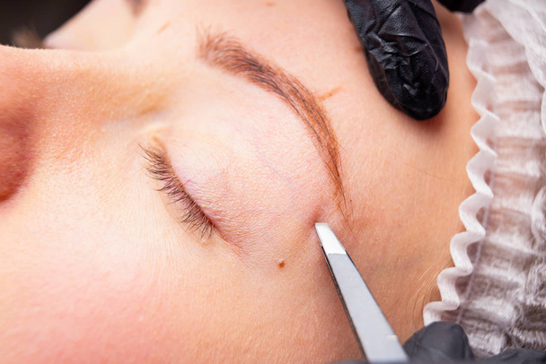 Cosmetic procedures for the treatment of eyebrows. Microblading in the beauty salon. Professional cosmetology. The process of applying the pigment - Photo, Image