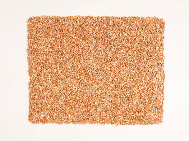 Buckwheat groats on beige color background. Healthy eating conce - Фото, изображение