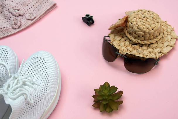 Sunglasses, straw hat, white sneakers on a pink background. Beautiful gentle flat lay. - Photo, Image