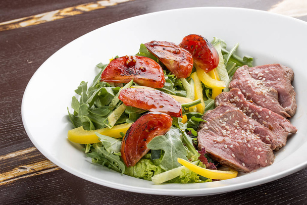 Salad with roast beef and sun-dried tomatoes on dark background - Photo, image