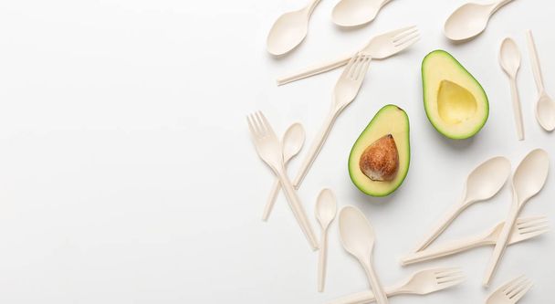 Halves of avocado and eco spoons and forks on white background - Zdjęcie, obraz