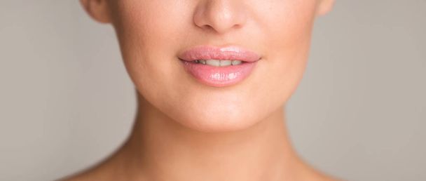 Lip augmentation. Woman with plump lips over gray background - Fotó, kép