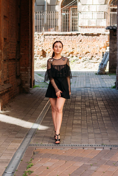 the girl is posing smiles. Emotional portrait of Fashion stylish portrait of pretty young woman. city portrait. brunette in a black dress. expectation. dreams - Фото, зображення