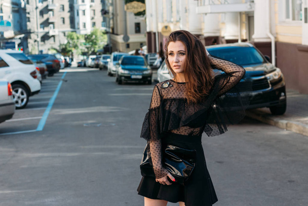 portrait of a girl, brunette, in a black dress, in the arch, in the city. posing, walking. alone in the crowd, loneliness - Φωτογραφία, εικόνα