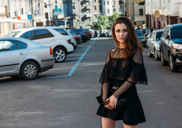 portrait of a girl, brunette, in a black dress, in the arch, in the city. posing, walking. alone in the crowd, loneliness - Фото, изображение
