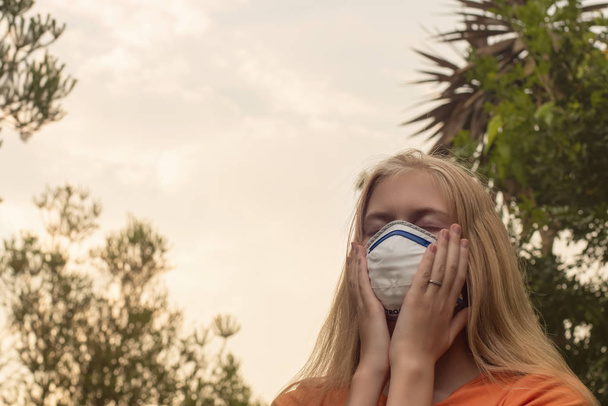 Avustralya çalı yangını: P2 N95 koruma maskesi takan sarışın kız çalıların dumanından nefes alan Pm2.5 parçacıklarının miktarını azaltmak için solunum maskesi. - Fotoğraf, Görsel