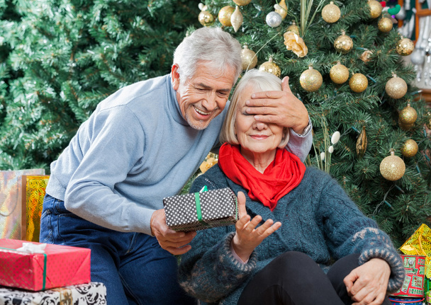 Senior Man Surprising Woman With Christmas Gifts In Store - Foto, immagini