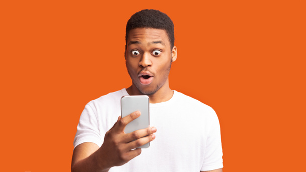 Closeup portrait of surprised african guy looking at phone - Foto, Bild
