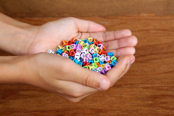 Kinderen hand houden kleurrijke kleine plastic kubus met het alfabet erop gedrukt. - Foto, afbeelding