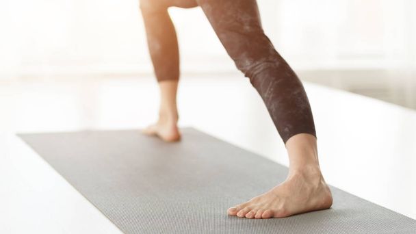 vrouw oefenen in krijger pose, staan op yoga mat - Foto, afbeelding