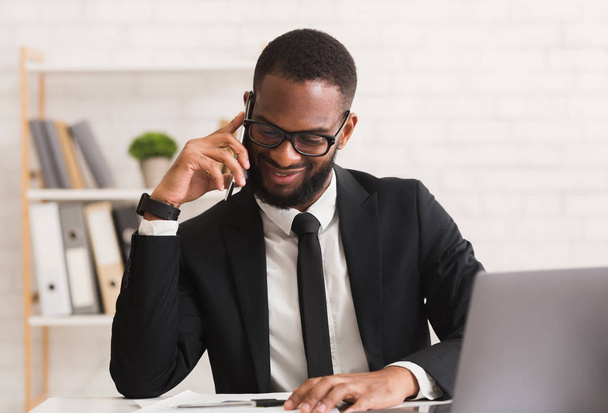 Onnellinen musta yrittäjä ottaa miellyttävä keskustelu kumppanin puhelimitse
 - Valokuva, kuva