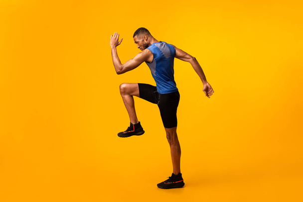 Jonge zwarte sportman loopt hoog tillen knieën - Foto, afbeelding