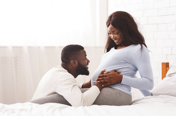 Attentive husband caressing his pregnant woman tummy - Photo, image