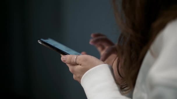 Handheld shot close up of woman hands typing on black phone - Video, Çekim