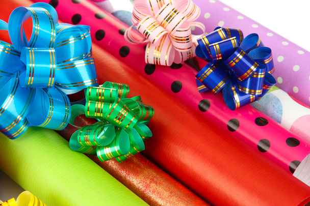 Rolls of Christmas wrapping paper with ribbons, bows isolated on white - 写真・画像