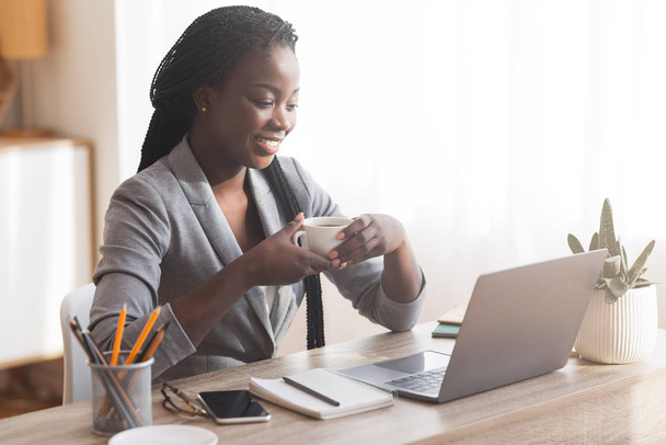 Exitosa mujer de negocios afro beber café en el lugar de trabajo en la oficina moderna
 - Foto, Imagen