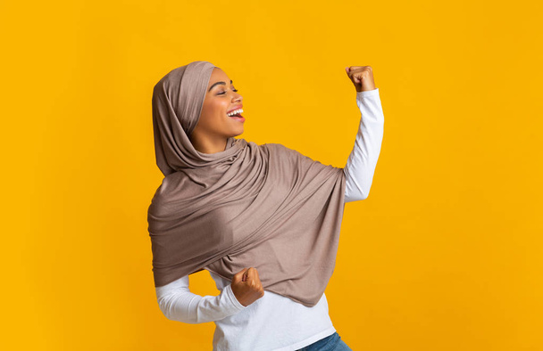 Afro fille musulmane dans le hijab célébrer le succès, lever la main avec excitation
 - Photo, image