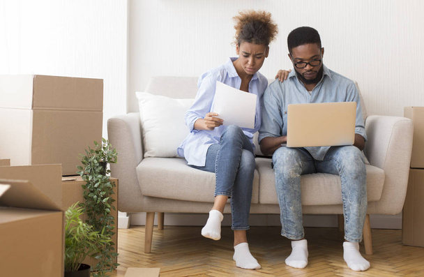 Serious Black Couple Reading Ownership Papers Sitting On Sofa Indoor - Foto, Imagen