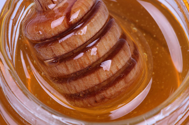 Honey in the jar with honey dispenser and wooden sticks - Foto, Imagem