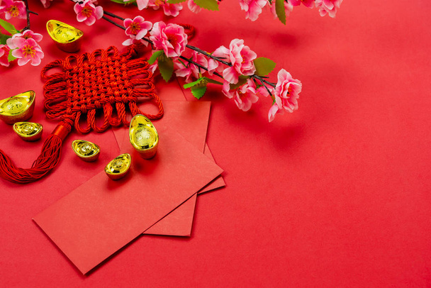 Chinese character means fortune and luck.Top view of Lunar New Year & Chinese New Year vacation concept background.Flat lay sign fortune with  pocket of money and pink cherry flower on red paper. - Photo, Image