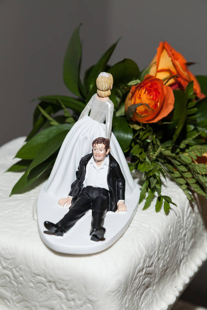 Funny figure; Bride and groom figurine in funny action on wedding cake. - Photo, Image