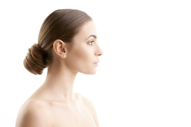 Woman face profile shot. Beautiful young woman with perfect skin looking away while standing at isolated white background.  - Фото, зображення
