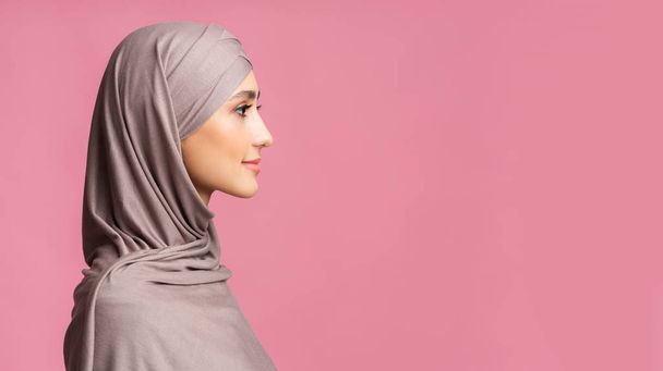 Retrato de perfil de mujer musulmana modesta en hijab sobre fondo rosa
 - Foto, Imagen
