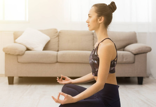 Jeune femme méditant dans l'atmosphère de la maison, pratiquant le yoga
 - Photo, image