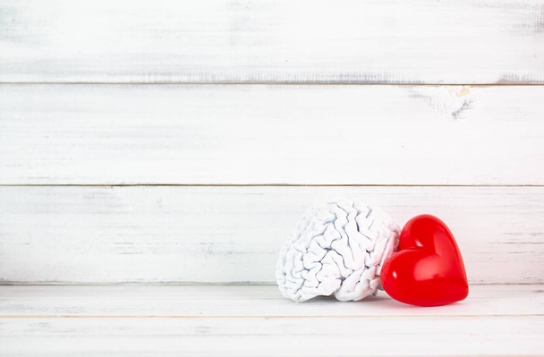 Corazón rojo con modelo de cerebro blanco sobre fondo de madera blanca. Sym.
 - Foto, imagen