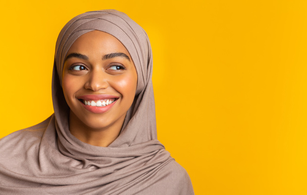 Красивая черная девушка в хиджабе смотрит в сторону копировального пространства, крупным планом
 - Фото, изображение