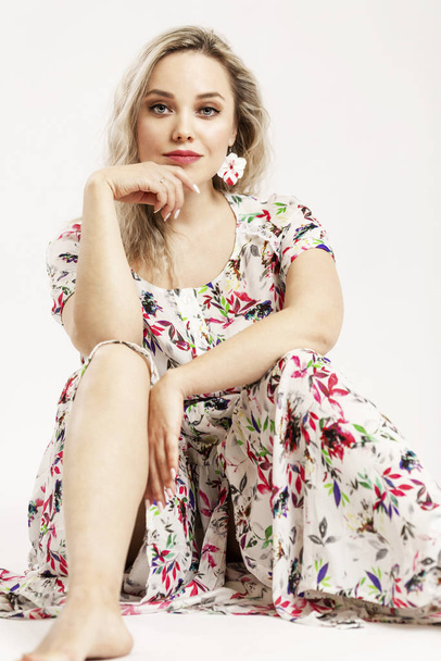 Beautiful smiling blonde in a romantic dress sitting on a white background.  - Valokuva, kuva