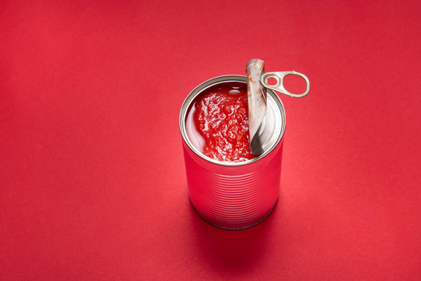 Opened tin can with canned tomatoes, on red background - Foto, Imagem