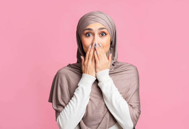 Σοκαρισμένη μουσουλμάνα με χιτζάμπ να καλύπτει το στόμα της με χέρια. - Φωτογραφία, εικόνα