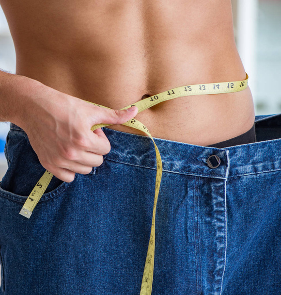 Uomo in pantaloni oversize nel concetto di perdita di peso - Foto, immagini