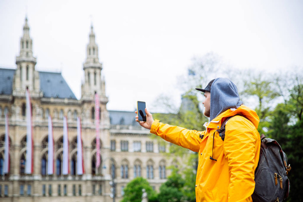 tourist traveler man taking picture on phone vienna city hall on background - Photo, Image