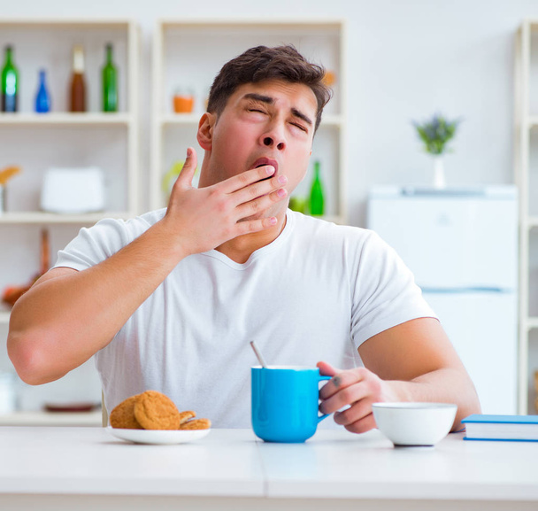 Man falling asleep during his breakfast after overtime work - 写真・画像