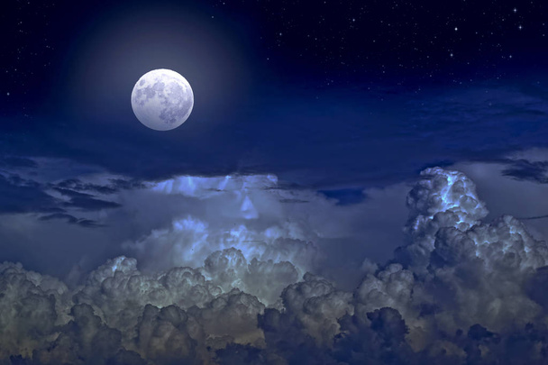De volle maan tussen de wolken in de nachtelijke hemel - Foto, afbeelding