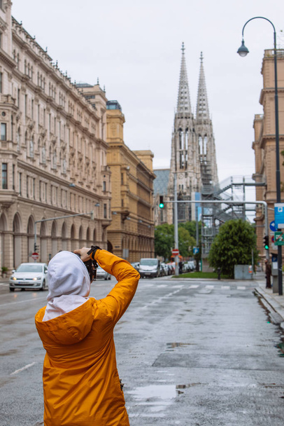 fotógrafo turista tomando fotos de la calle de la ciudad con iglesia votiva en el fondo
 - Foto, imagen