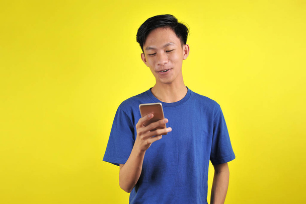 Boldog fiatal jóképű ázsiai férfi mosolygós okostelefon - Fotó, kép