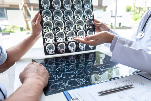 Arzt hält Röntgenfilm in der Hand und untersucht Gehirn durch c - Foto, Bild