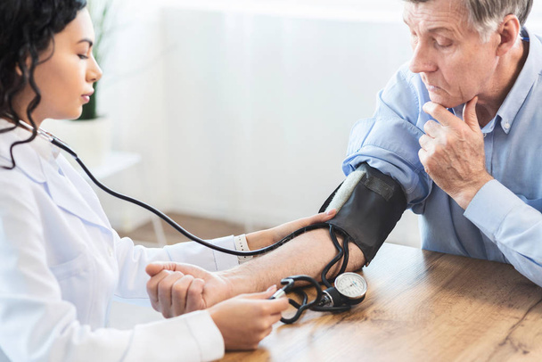 Žena zdravotní sestra kontrolu krevního tlaku dospělých mužů - Fotografie, Obrázek