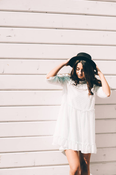 retrato de mujer hipster con estilo joven, con vestido blanco de moda, sombrero negro y botas
 - Foto, Imagen