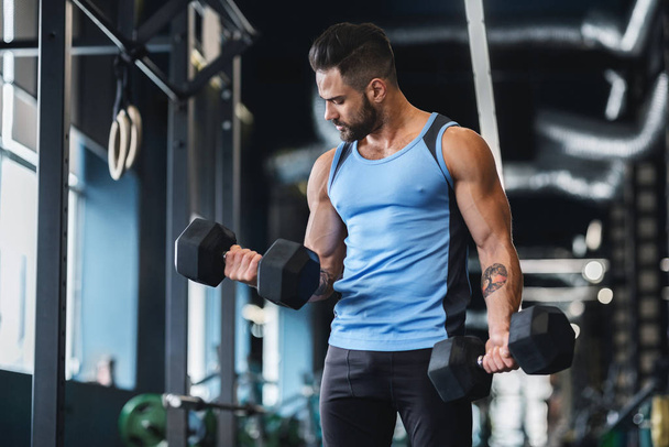 Hombre musculoso fuerte haciendo ejercicios con pesas
 - Foto, imagen