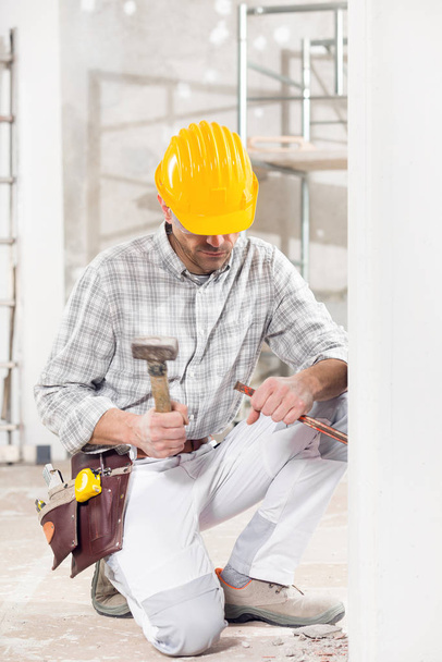 Builder kneeling using a chisel and mallet - Photo, Image