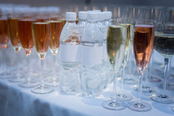 buffet sul tavolo ci sono bottiglie di acqua pulita accanto a bicchieri di vino bicchieri di vino rosso e bianco
 - Foto, immagini
