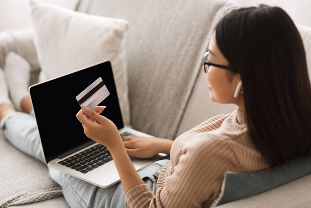 Tyttö maksaa verkossa luottokortilla ja kannettava tietokone
 - Valokuva, kuva